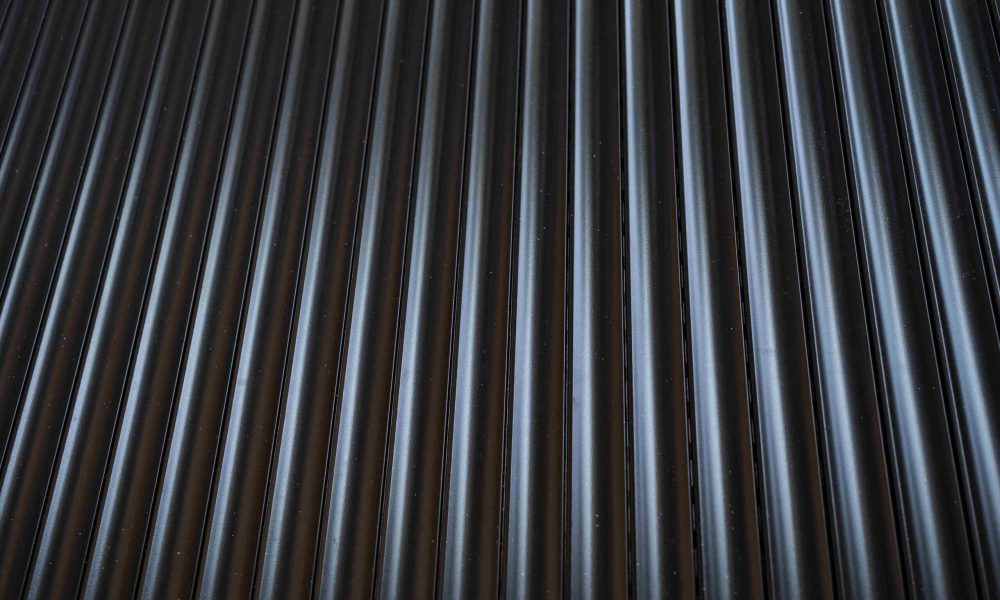 Close-up view of evenly spaced, vertical black metal or plastic ridges or grooves, similar to materials used in roofing projects by Aleman Roofing.
